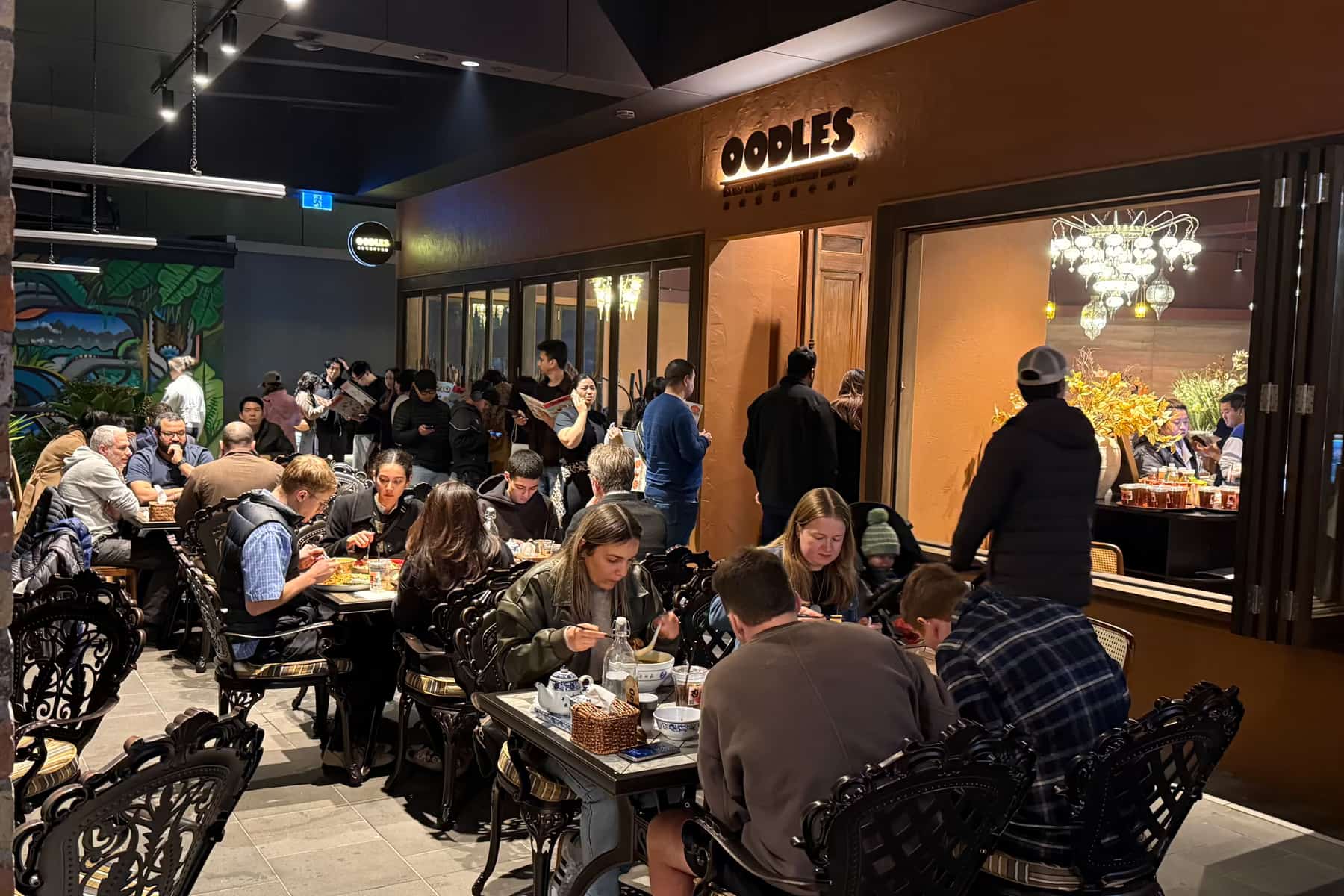Busy Oodles dining room beneath the restaurant sign